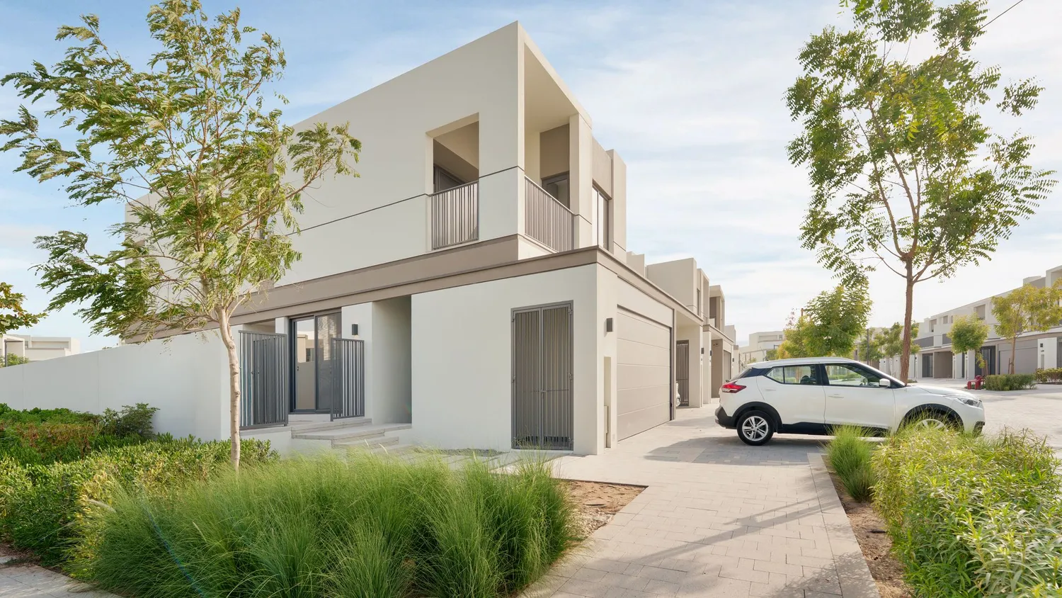 A contemporary two-storey townhouse behind planted verges on a quiet residential street