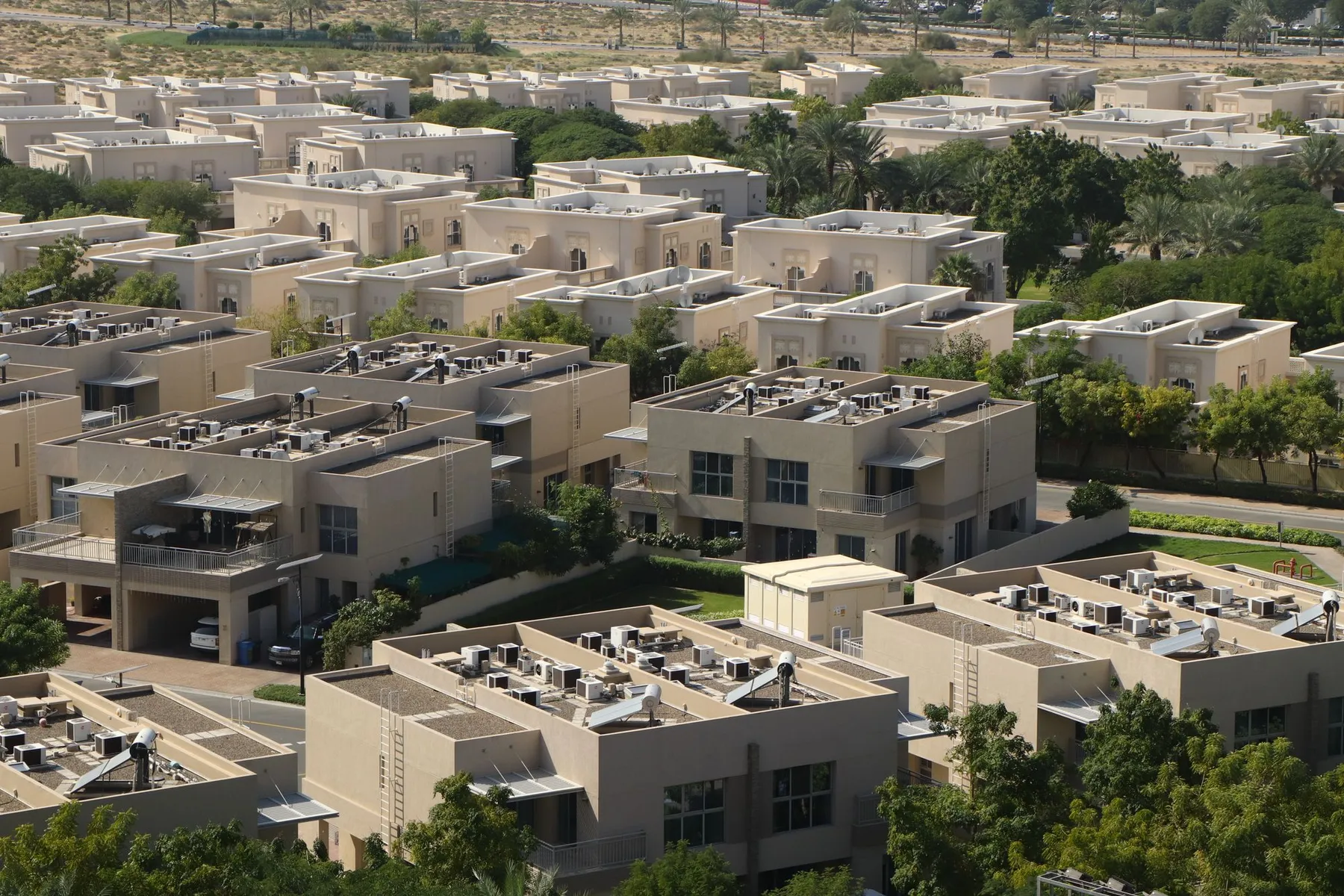 Aerial view over clusters of low-rise villas and townhouses among trees in the UAE